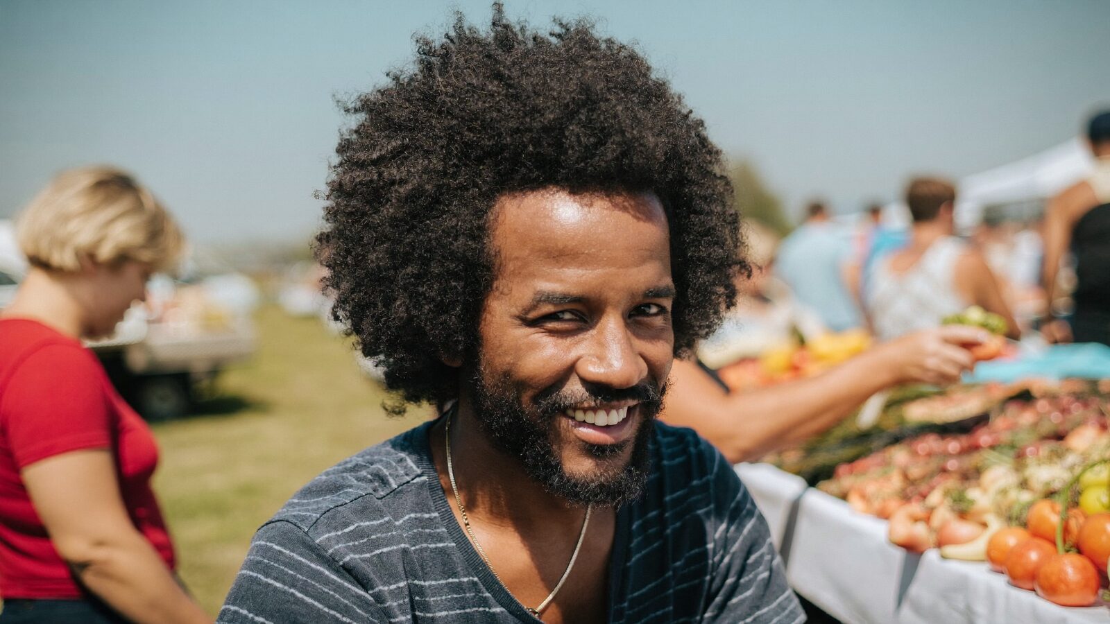 Man in his late 30s with a full, natural hairline smiling on a lakeside dock at sunset, shown in three-quarter view